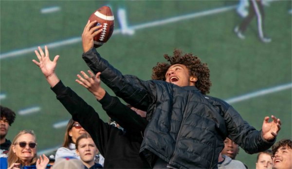  A football fan reaches out in an attempt to catch a football kicked into the crowd.