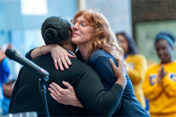  A faculty member hugs a student after a speech.