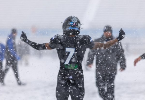 A football player holds up his hands during heavy snowfall. 